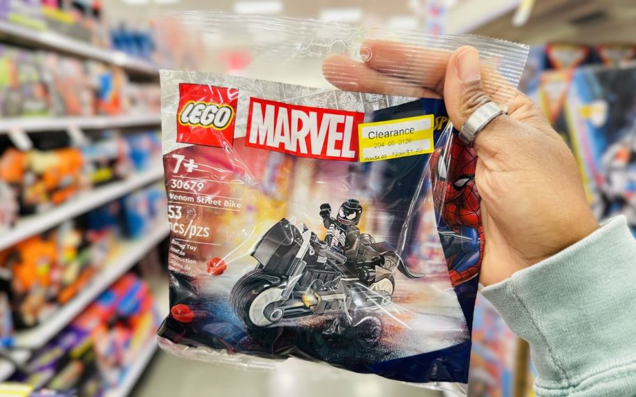 a womans hand holding a LEGO marvel venom street bike building set