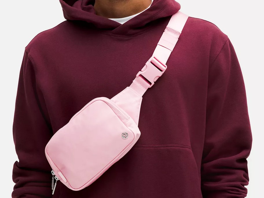 man in maroon hoodie with pink belt bag across chest