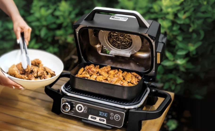 chicken wings cooking on a woodfire gril on a wooden tabletop