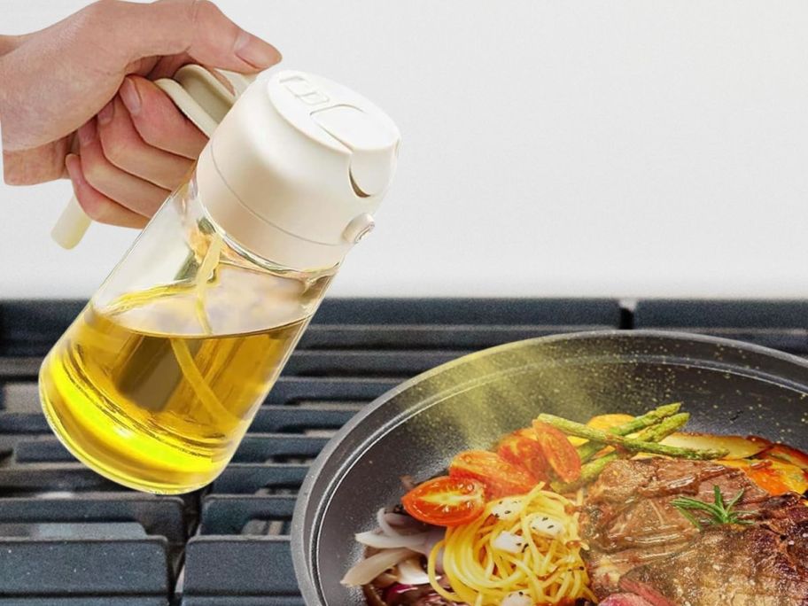 hand using olive oil dispenser to spray oil in steak