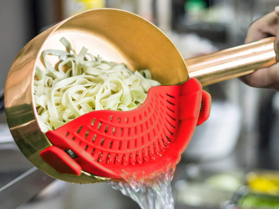 pan with noodles inside being strained