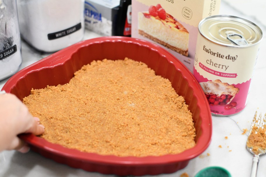 pressing a graham cracker crust into heart shaped pan 