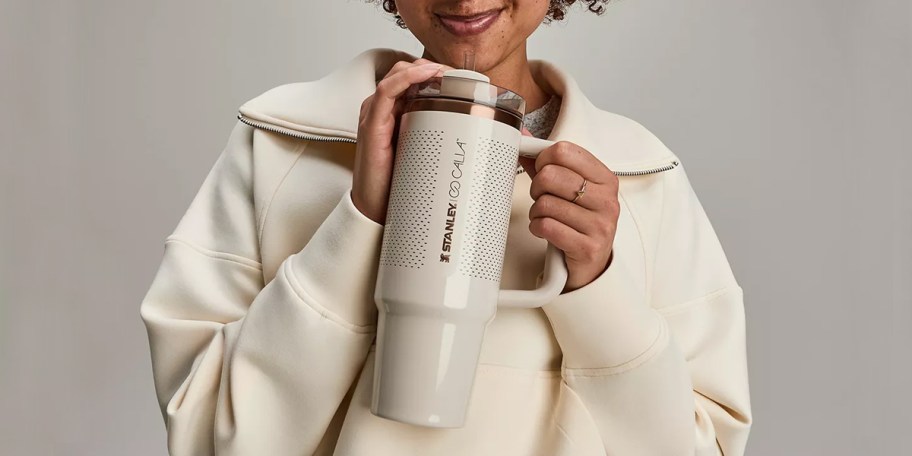 woman holding beige stanley tumbler