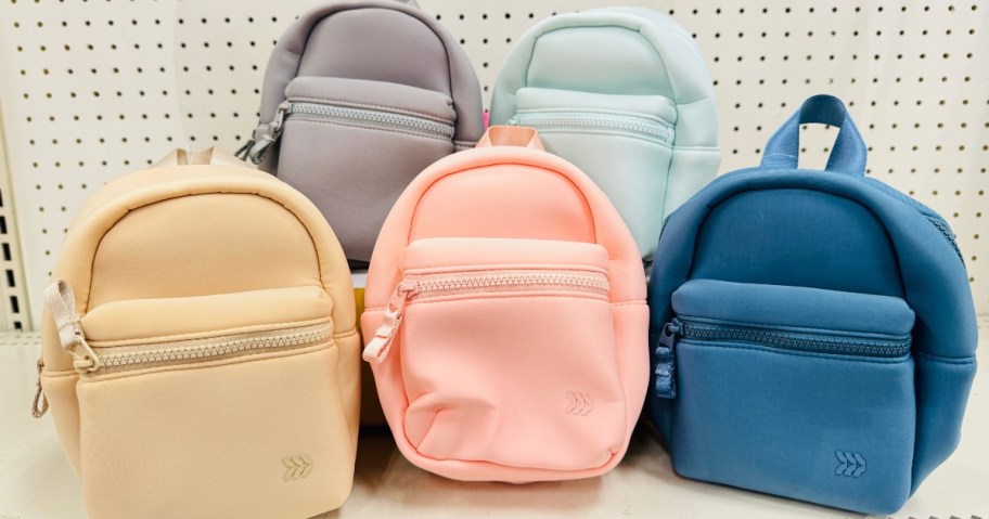 5 different color mini backpacks on a store shelf