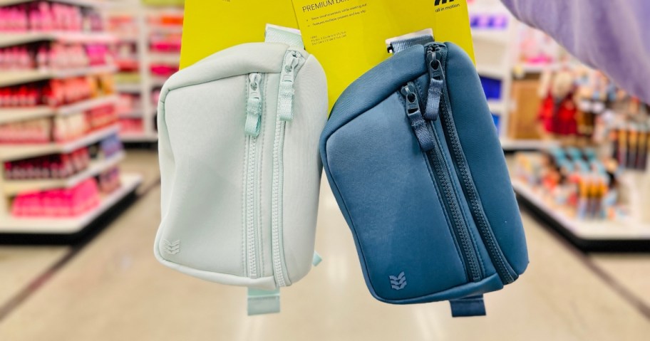 hand holding a light blue and a dark blue double zipper belt bags in a store aisle