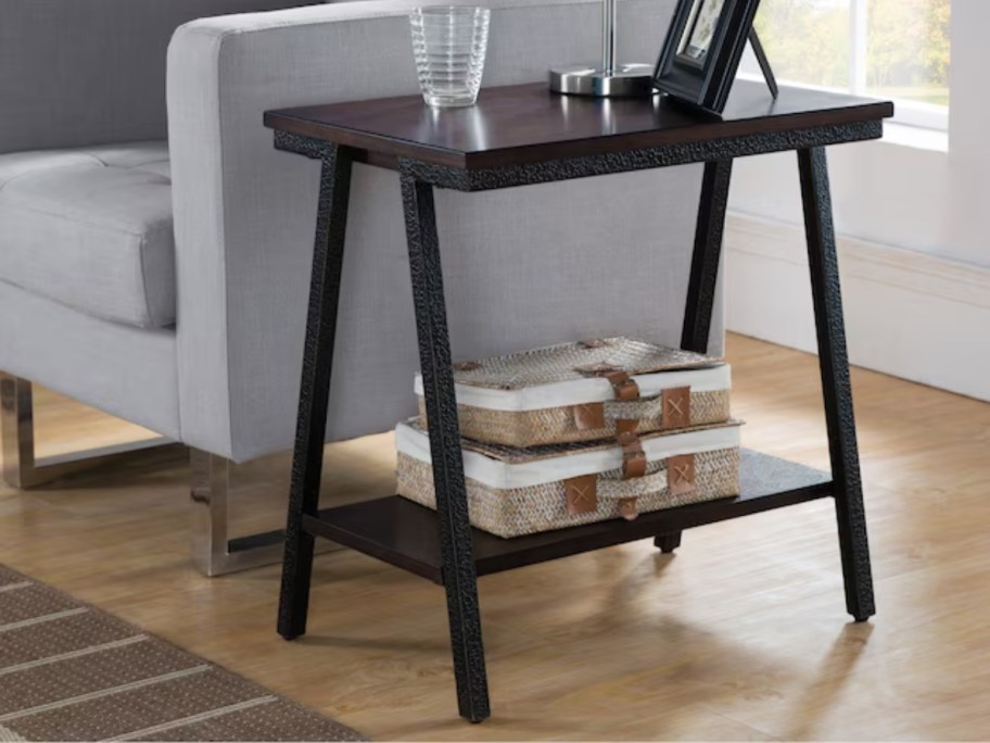 a dark brown contemporary style wood end table by a grey accent chair