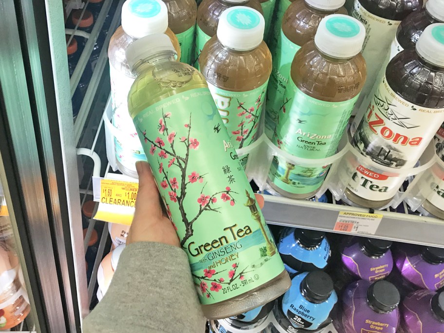 hand holding a bottle of Arizona Green Tea inside refrigerator case in store