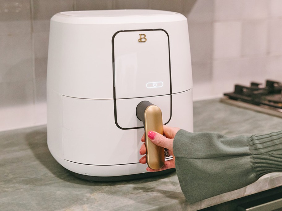 hand grabbing handle on white drew barrymore air fryer