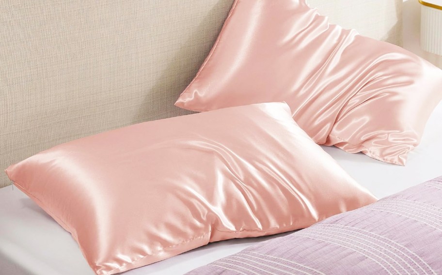 set of two pink satin pillows on a bed