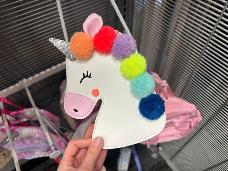 A person holding a Cat & Jack Pom Pom Unicorn Crossbody