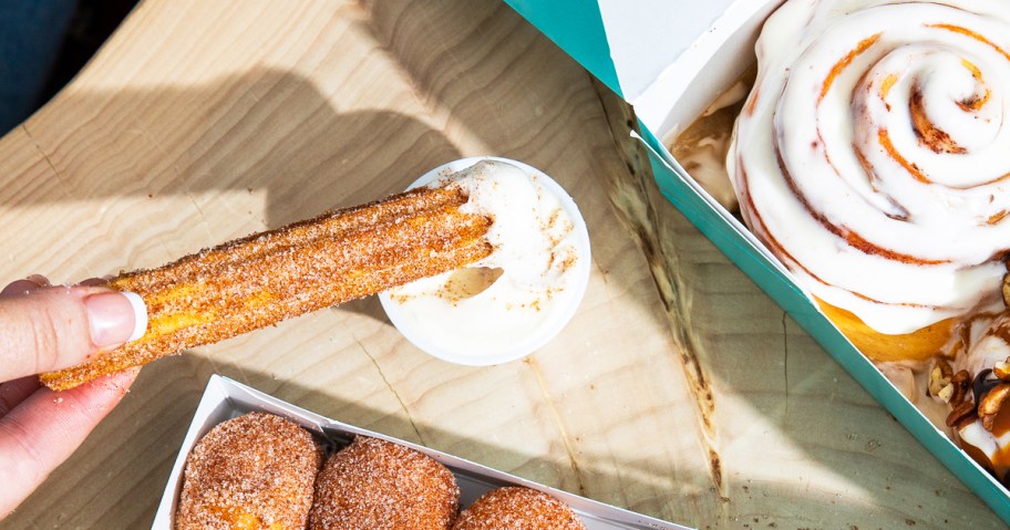 dipping a churro into cup of icing