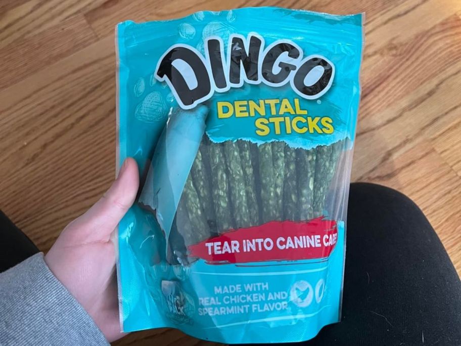 A person holding a bag of Dingo Dog Dental Treats