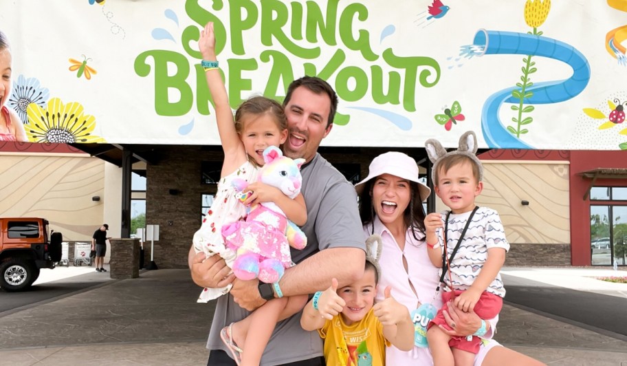 family at great wolf lodge in front of spring breakout sign