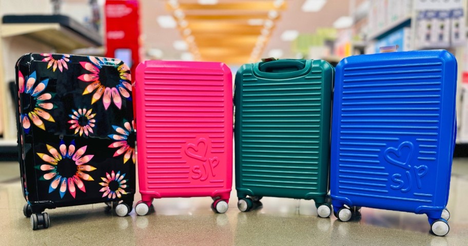 four hardside spinner wheel suitcases, one is black with multicolor flowers, the other 3 are solid color with a ridged design, one is pink, one is green, and one is blue