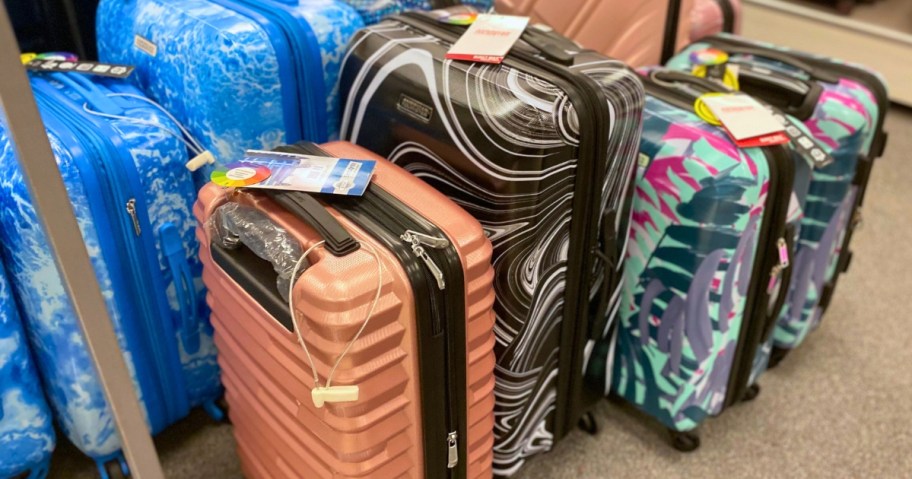 various hardsided spinner luggage pieces in pinks, blue prints, and tropical prints in a store