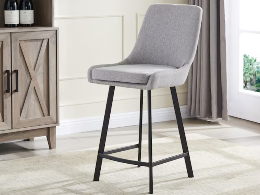 a grey upholstered bar stool sitting in a living room