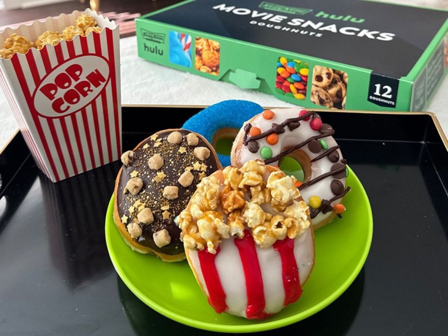 A plate Krispy Kreme's Hulu Movie Snacks Doughhnuts next to a container of popcorn