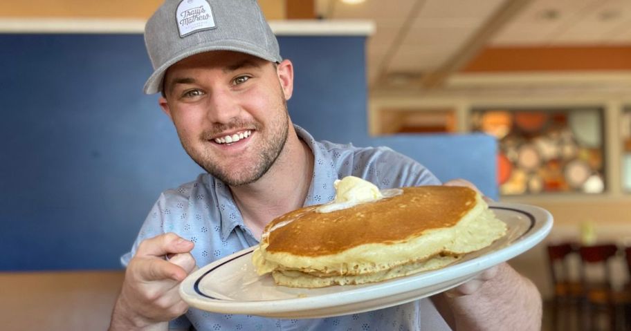 Man holding a plate of IHOP pancakes