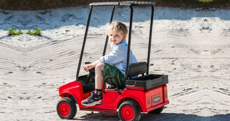 Kid riding in an electric golf cart on sand