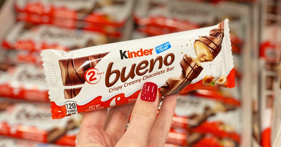 woman with red nails holding a Kinder Bueno candy bar