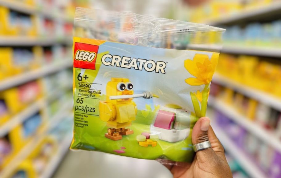 a womans hand holding a LEGO easter chick building kit