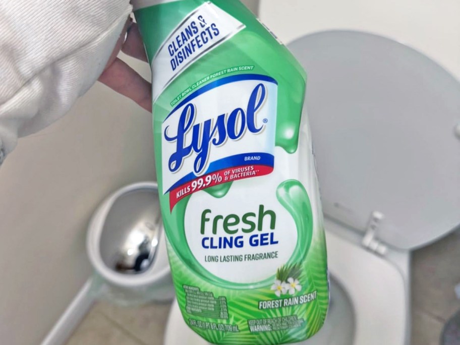 holding a green bottle of Lysol Toilet Bowl Cleaner Gel in bathroom