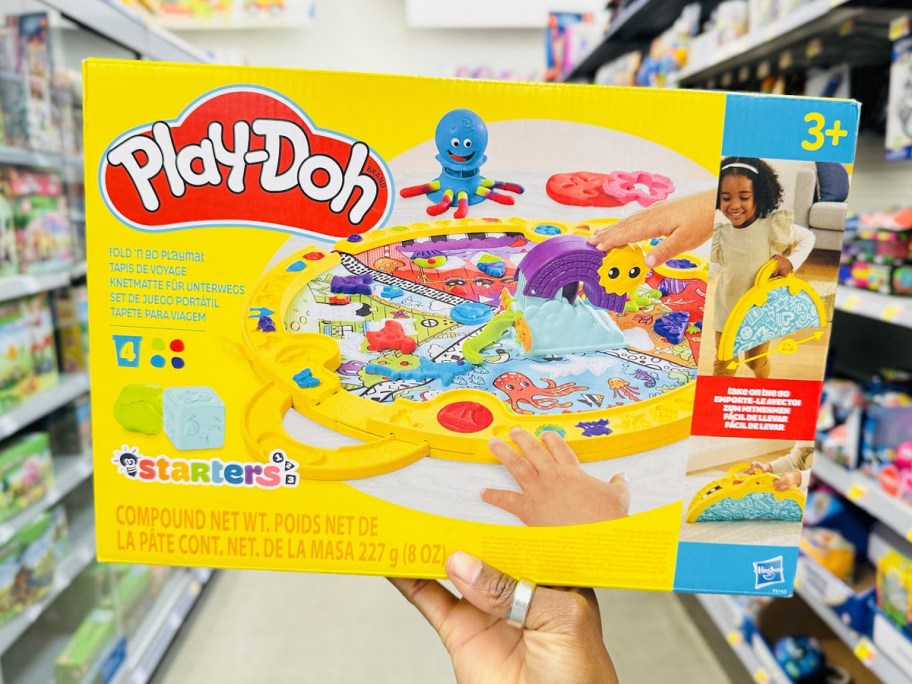 hand holding up Play-Doh Fold & Go Playmat box in store