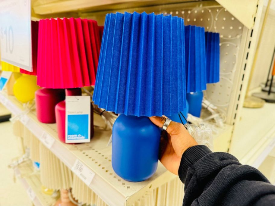 A person holding a small blue lamp in a store