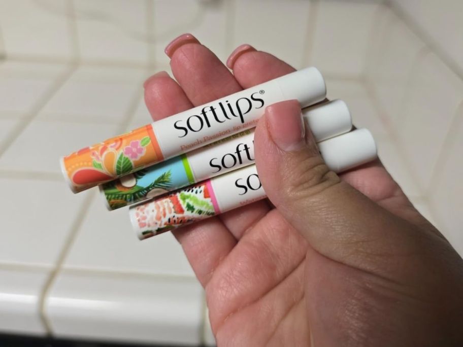 A person holding a 3-Pack of Softlips chapstick 