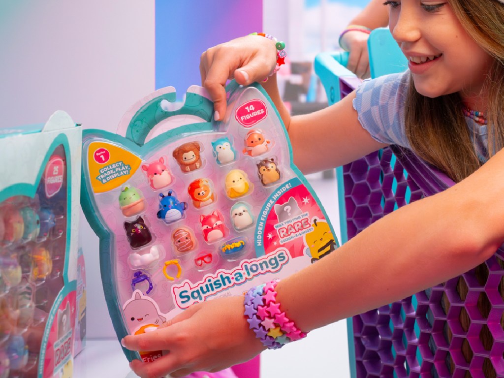 little girl grabbing Squishmallows Squish-a-longs from store shelf