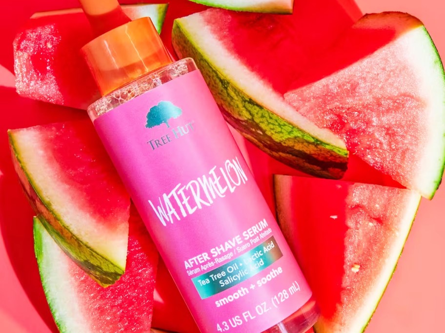 pink bottle of Tree Hut After Shave Serum on top of watermelon slices
