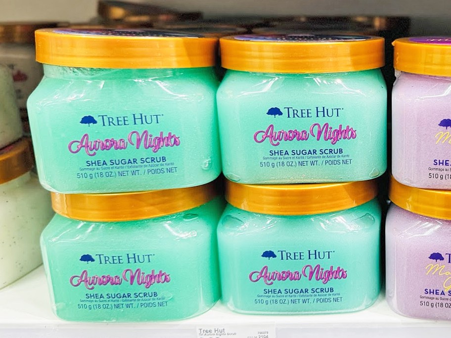 stacked green jars of Tree Hut Aurora Nights Shea Sugar Scrub on store shelf