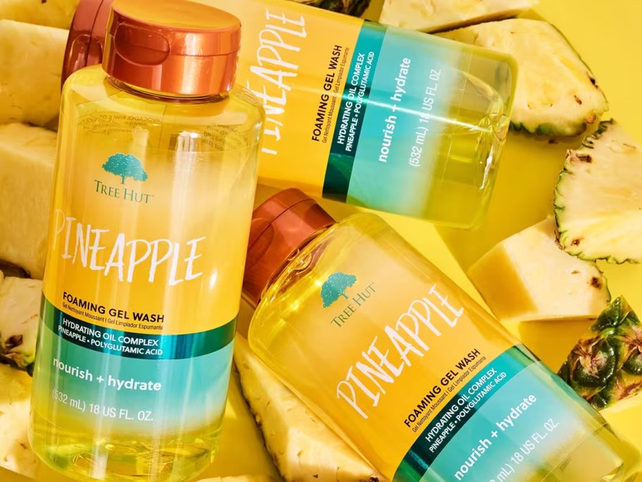 yellow bottles of Tree Hut Foaming Gel Body Wash on top of pineapple slices