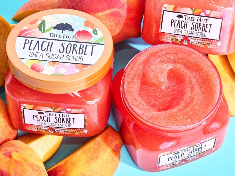 jars of Tree Hut Peach Sorbet Shea Sugar Body Scrub surrounded by peach slices