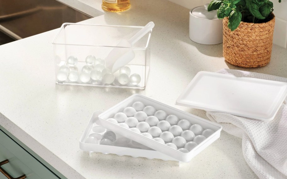 a white Ice Cube Tray with a clear bin that has some cubes in it and scoop sitting on a counter