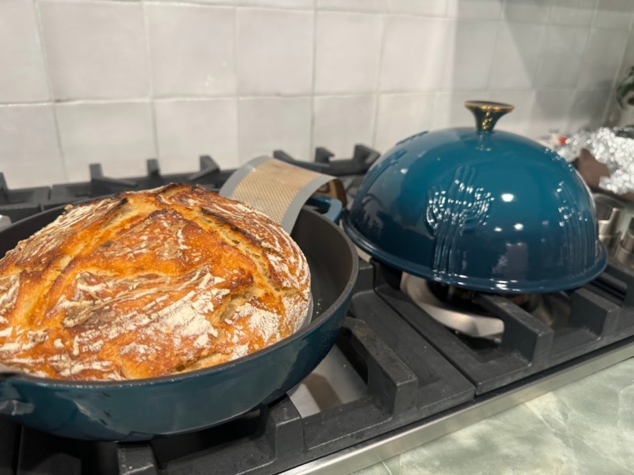 dark teal cast iron bread oven sitting on top of an oven with a fresh loaf of sourdough in it