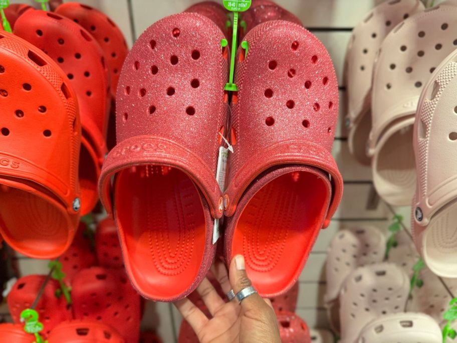 Crocs Classic Glitter Clogs in Cherry Red hanging in store