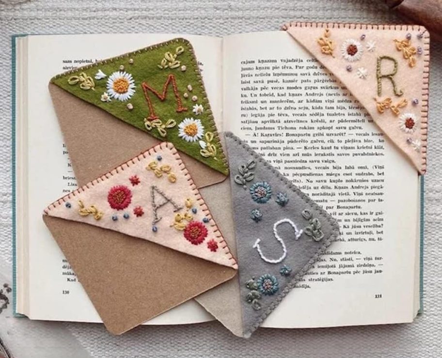 felt monogram corner bookmarks with stitched flowers laying on open pages of book