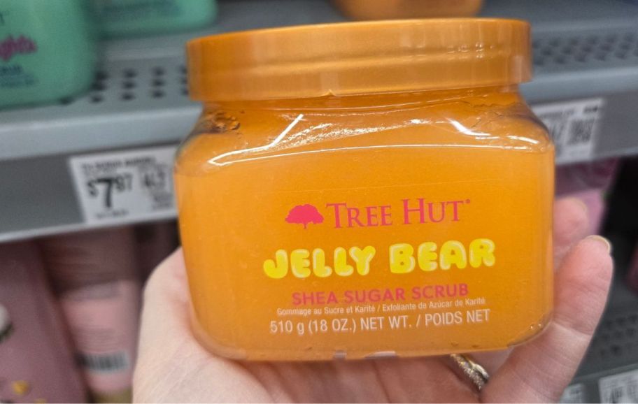 a womans hand holding a jar of jelly bear sugar scrub