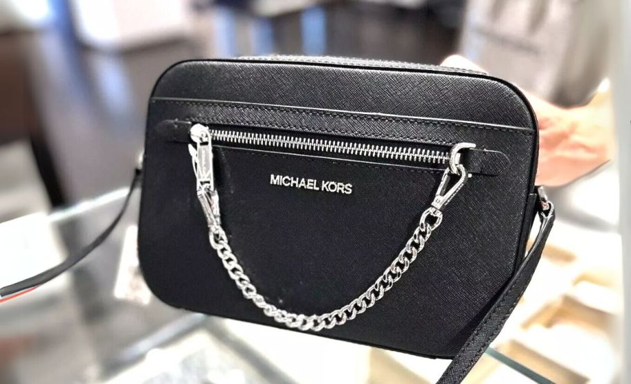 a black michael kors jet set crossbody on a glass countertop