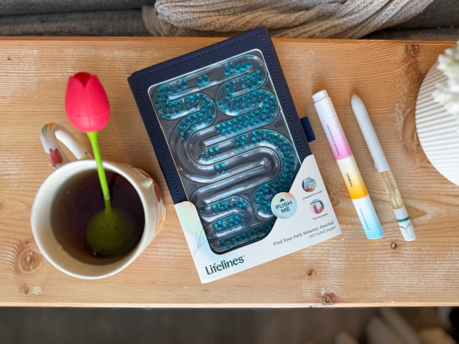 lifelines journal laying between a cup with a tulip diffuser and two lifeline pens