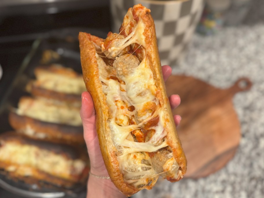 hand holding cheesy meatball sub