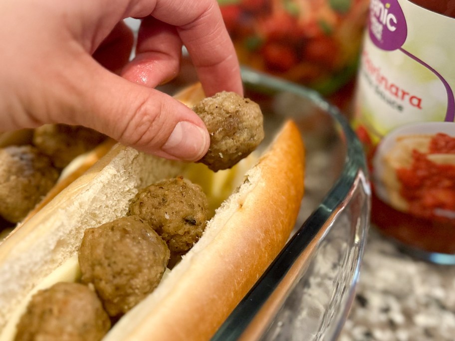 hand putting meatball on roll