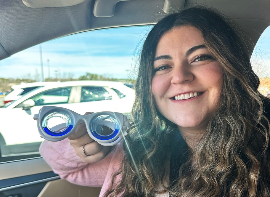 Young woman holding a pair of motion sickness glasses in a car