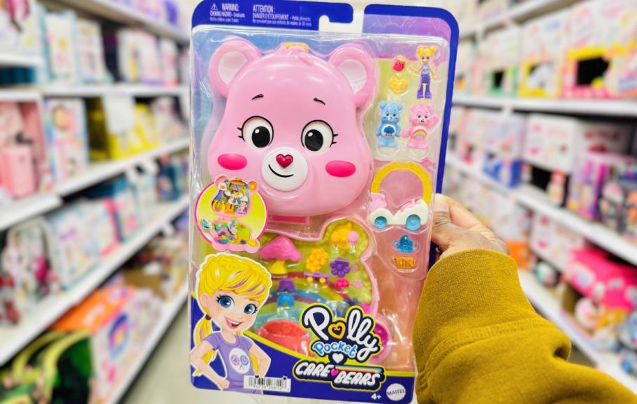 a womans hand holding a packaged polly pocket care bears playset