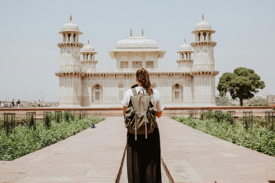 woman wearing bookbag in front of intricate building