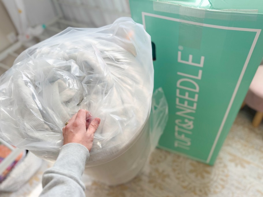 rolled up tuft and needle mattress next to box