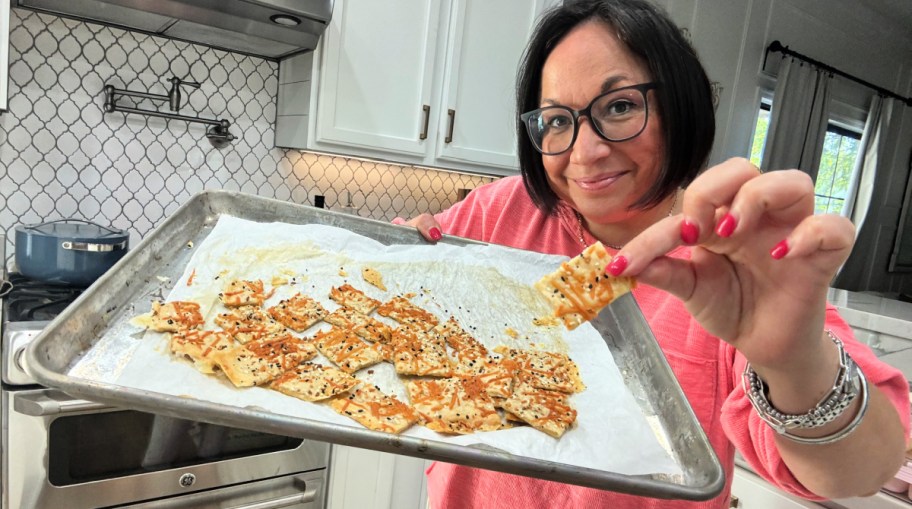 woman holding a sheet pan with sourdough crackers