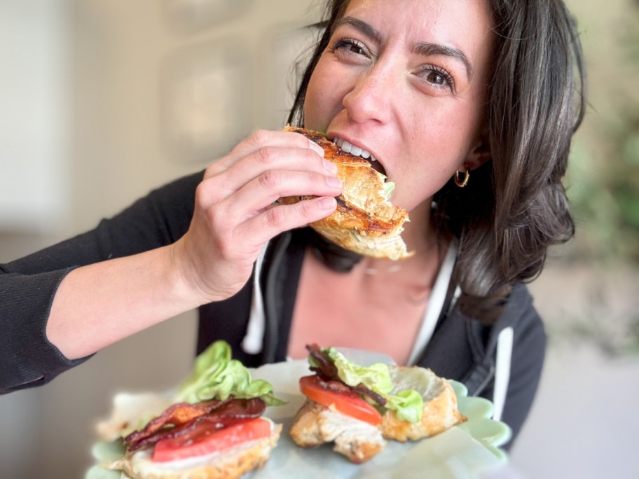 woman taking bit of BLT chicken sandwich