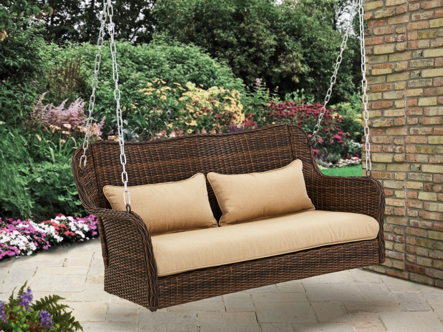 wicker porch swing with tan cushions